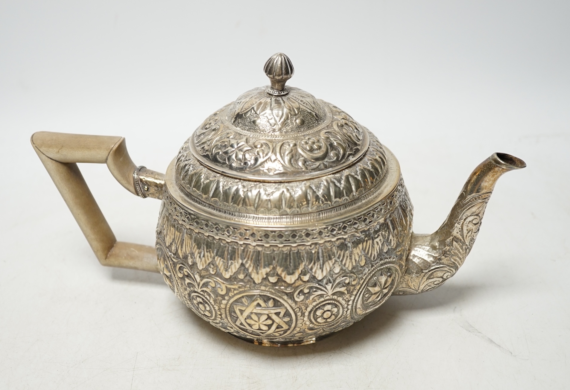 An Indian silver metal teapot with embossed and chased decoration, gross weight 16.9oz. Condition - poor to fair